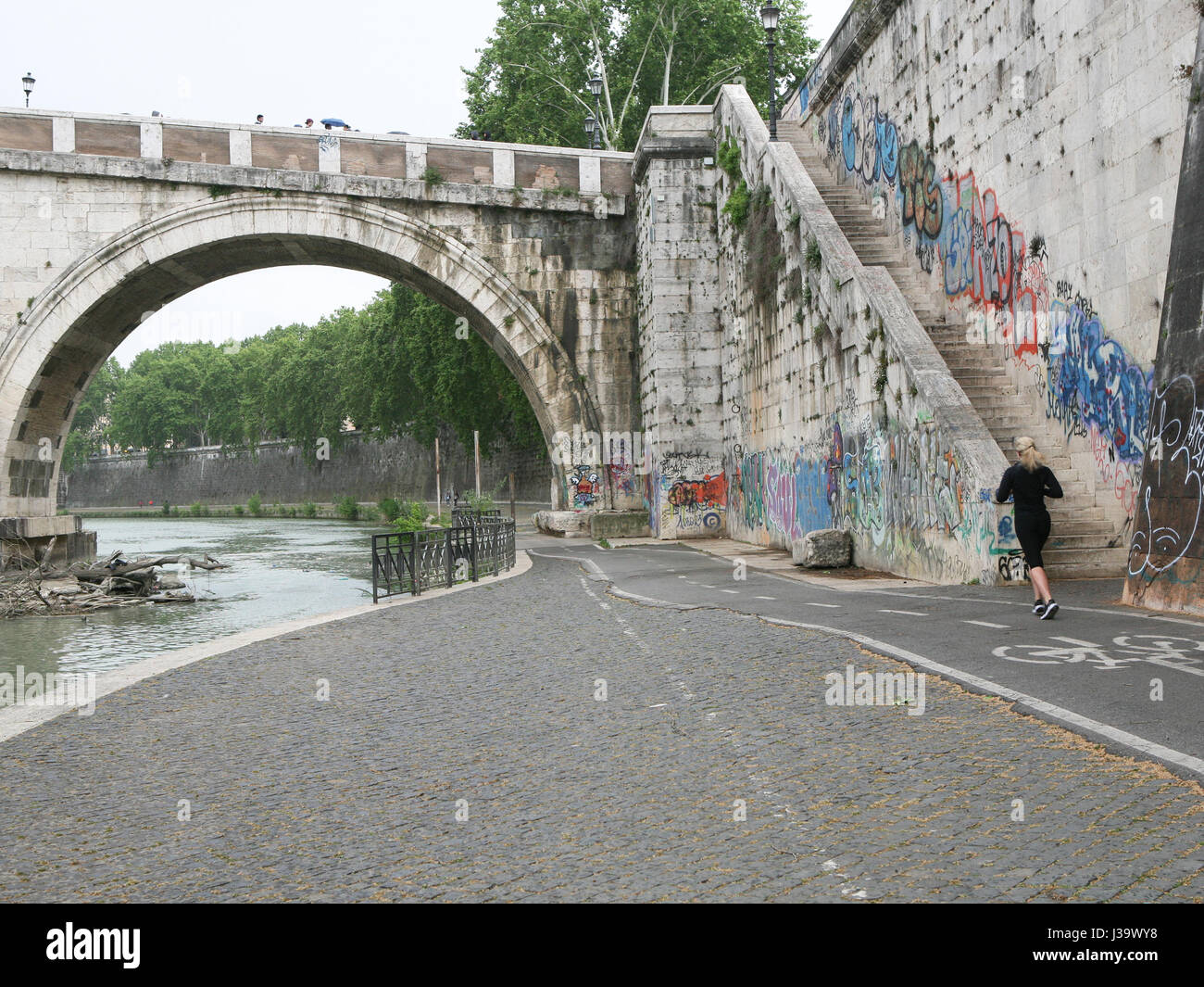 La donna in esecuzione sulla pista ciclabile al di sotto del fiume Tevere a Ponte Sisto ponte, Roma, Italia Foto Stock