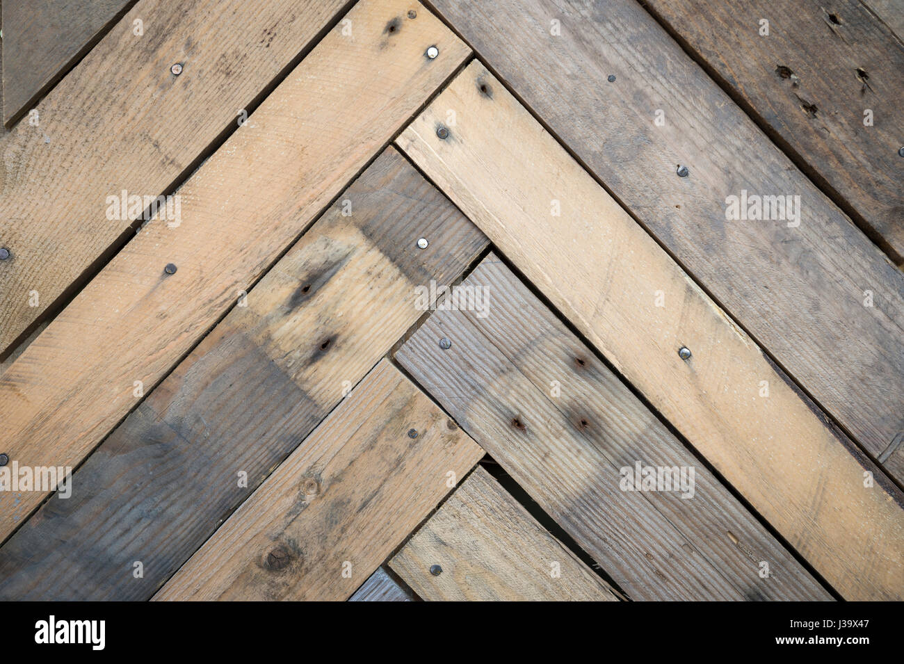 Texture di sfondo weathered listoni in legno con macchie e chiodi disposti in una struttura a lisca di pesce Foto Stock