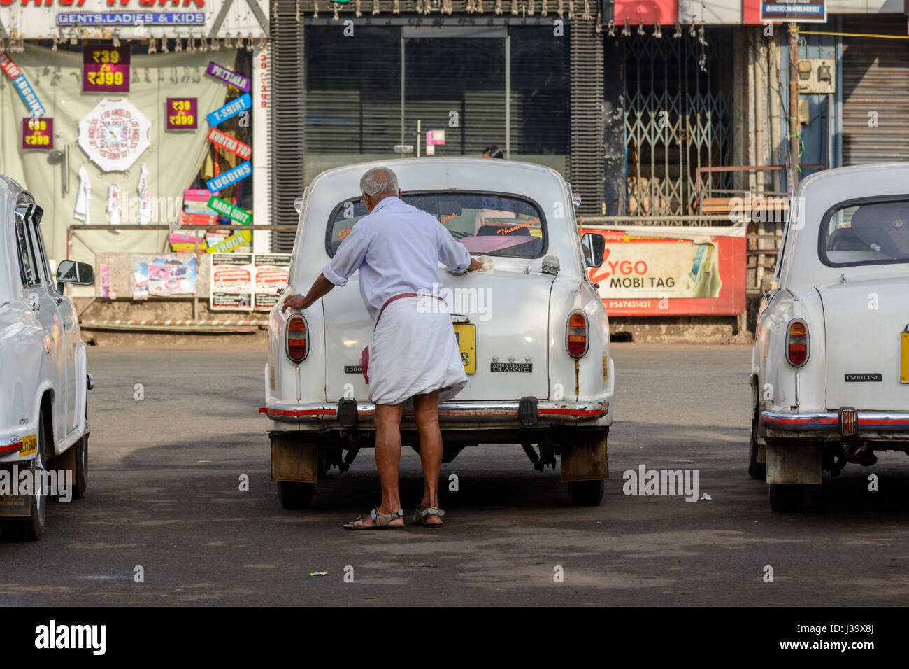 Un uomo anziano pulisce il suo ambasciatore auto in strada in Thalassery (Tellicherry), Kannur district (Cannanore), Kerala, India del Sud, Sud Asia Foto Stock