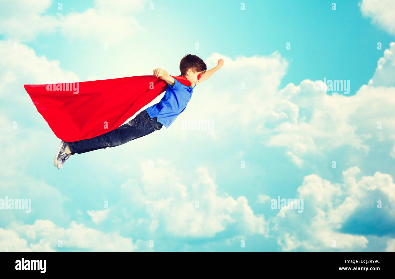 Ragazzo in rosso superhero cape e maschera sorvolano sky Foto Stock