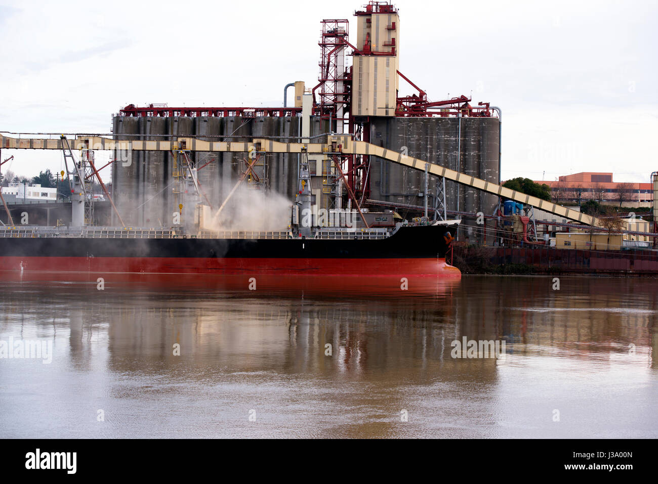 La grande nave sul fiume Willamette in Portland Oregon è caricato con carichi alla rinfusa, laminazione in una nuvola di polvere, contaminando l'ambiente Foto Stock