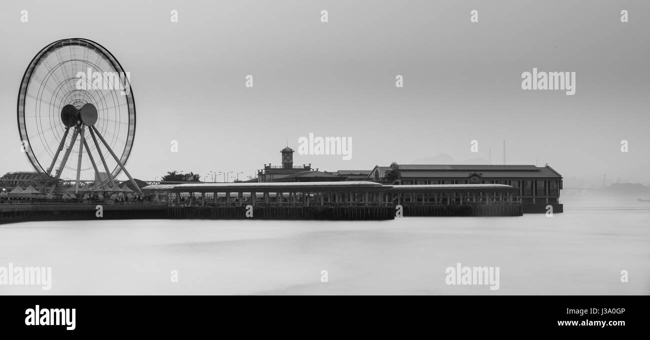 Pier 9, Central Hong Kong. La grande ruota si siede forefront sul Victoria Harbour, una grande attrazione turistica. Foto Stock