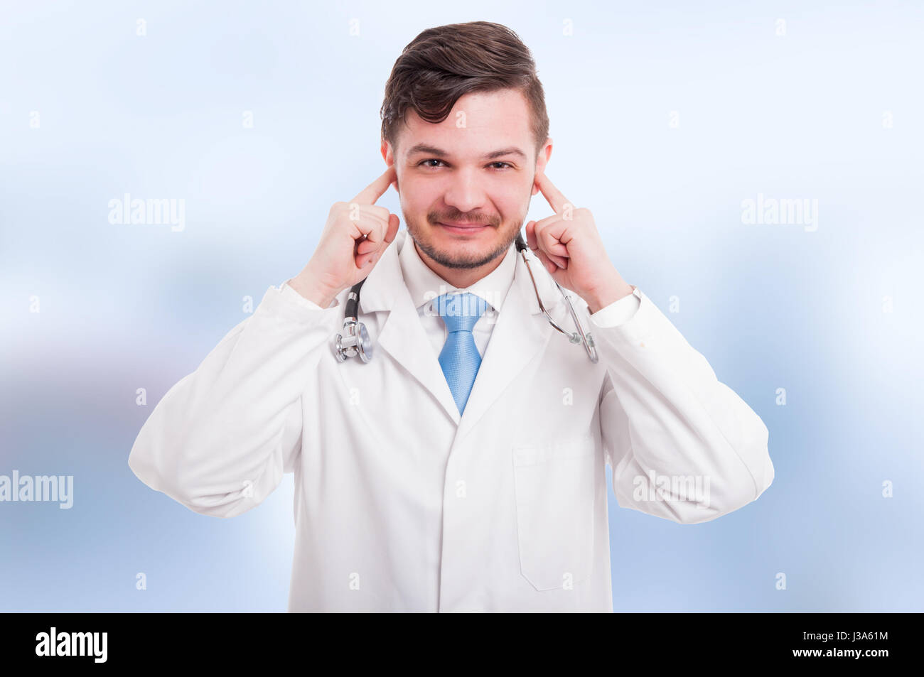 Felice attraente medic che copre le sue orecchie come non sentire male concetto su sfondo blu Foto Stock