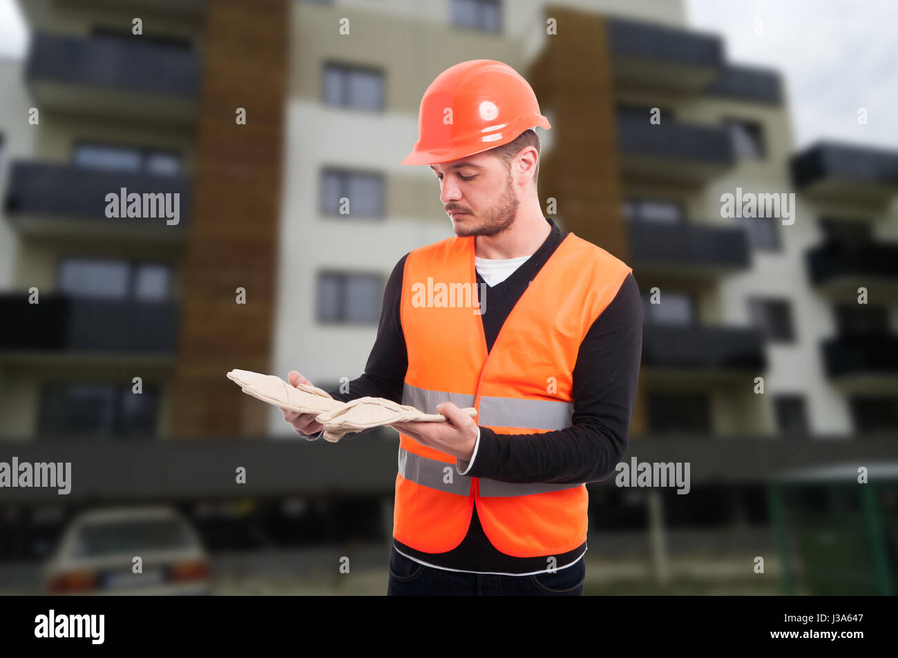 Costruttore maschio per esterno al luogo di lavoro tenendo la sua guanti di protezione Foto Stock