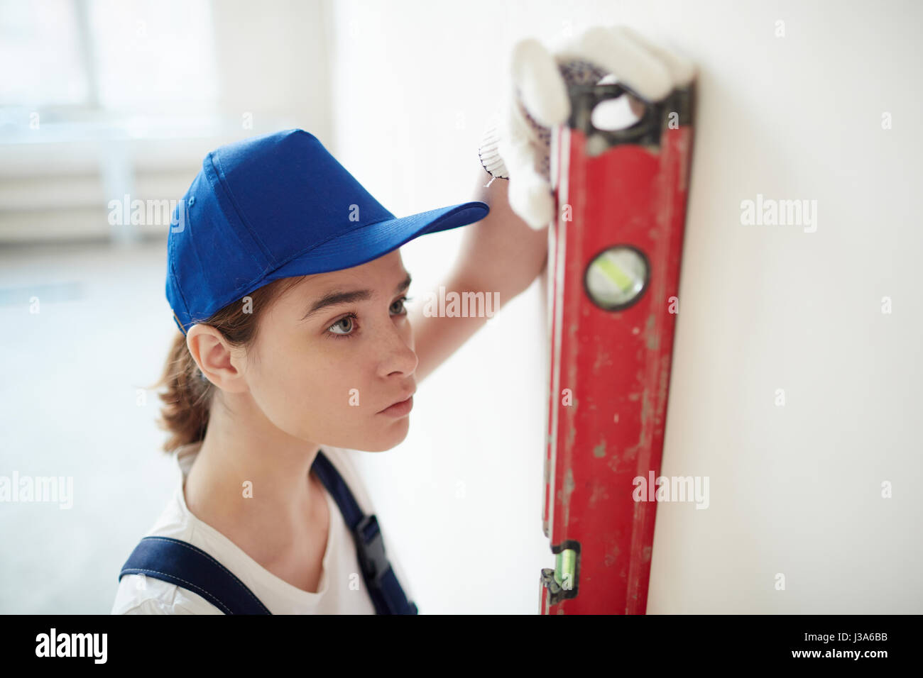 Lavoratore di sesso femminile che verifica i livelli di parete Foto Stock