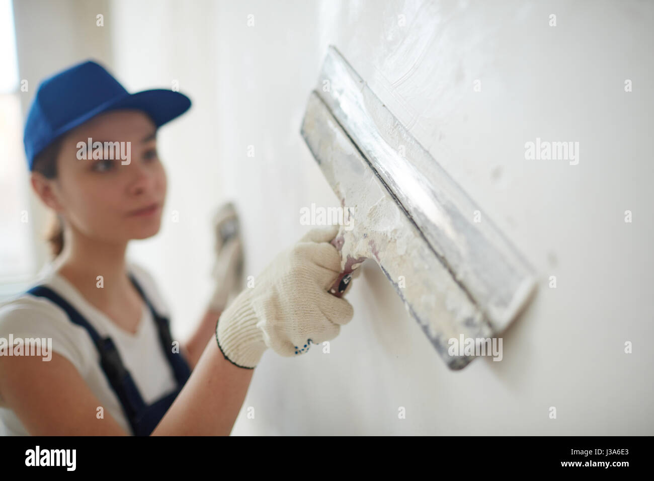 Lavoratore di sesso femminile che lisciatura pareti Foto Stock