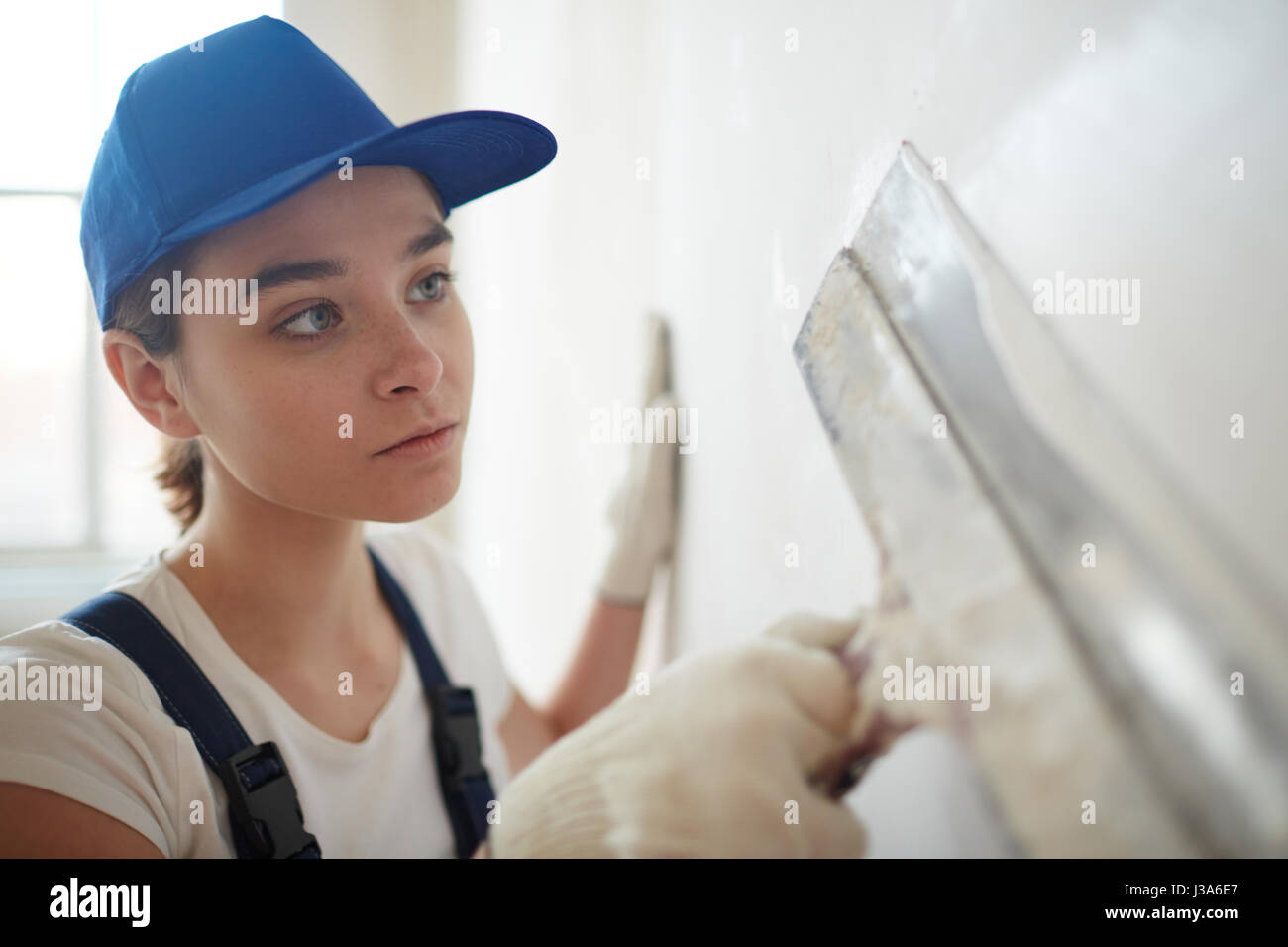 Donna intonacatura di pareti con la spatola Foto Stock