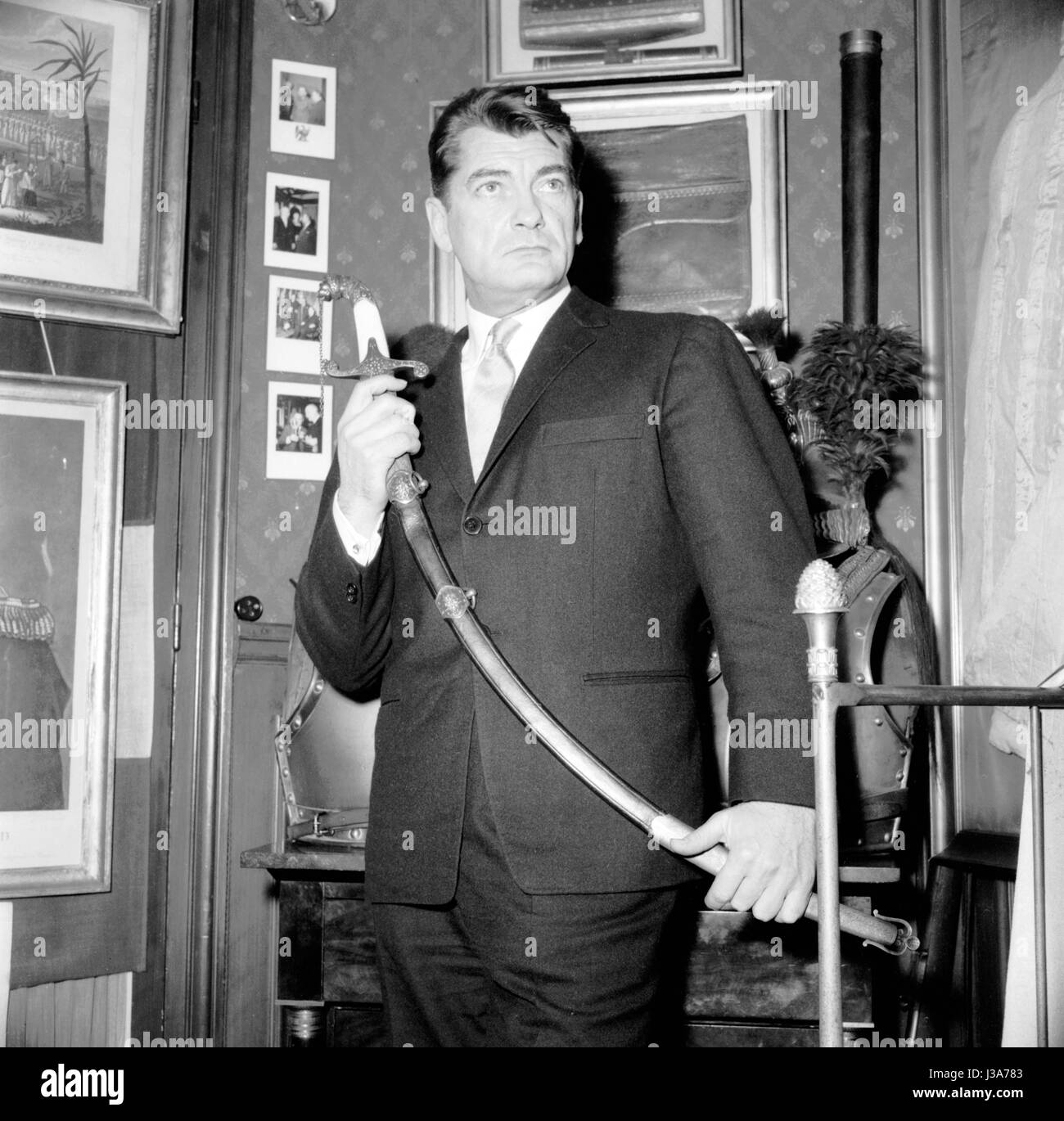 Attore francese Jean Marais in posa l'appartamento del fotografo Rétif de la Bretonne. Egli è in possesso di una spada dal periodo di ispirazione "IMPERO". 1955 Foto Stock