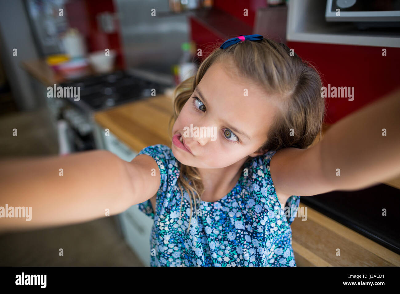 Ragazza tirando funny faces in cucina a casa Foto Stock