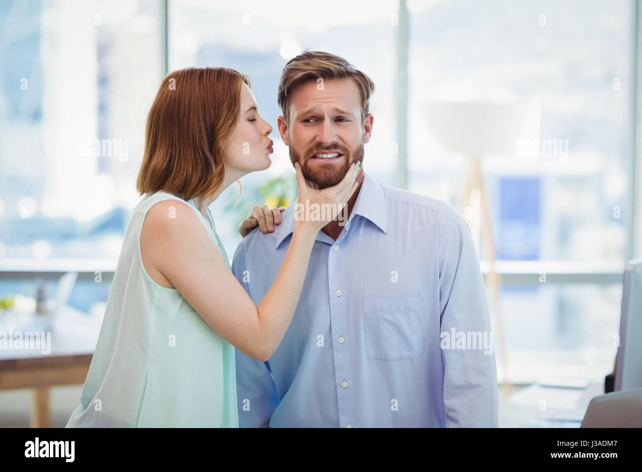 Donna affettuosa baciare Uomo in ufficio Foto Stock