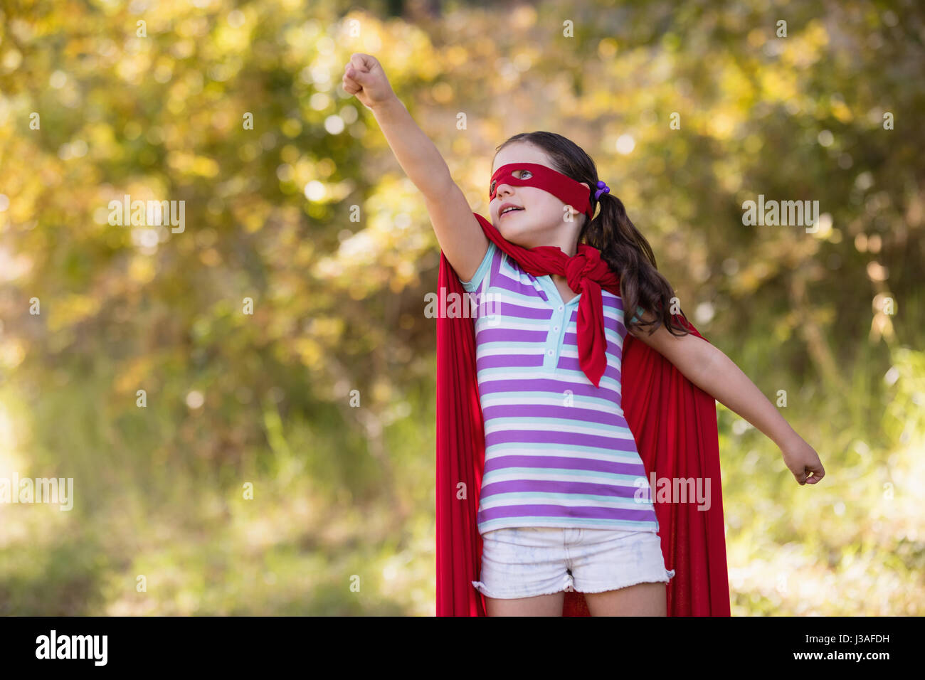Bambina cercano di volare indossando il costume del supereroe in campeggio Foto Stock