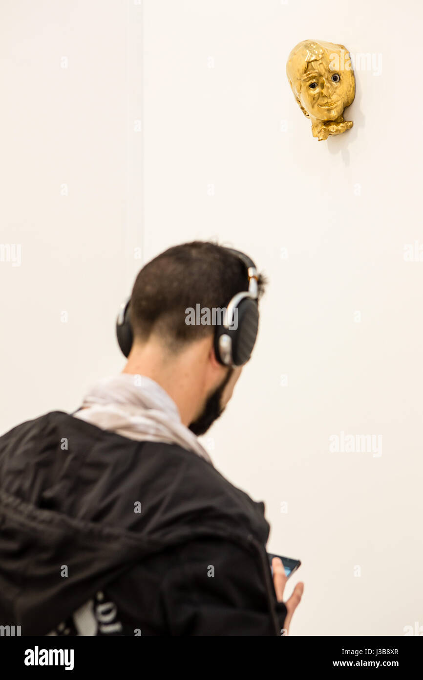 New York, US. 05 Maggio, 2017. New York, NY - 5 maggio 2017. Il giorno di apertura del fregio Art Fair, presentazione di arte moderna e contemporanea presentata da gallerie provenienti da tutto il mondo, su Randall's Island in New York City. Un visitatore con le cuffie in Sprüth Magers stand, sorvegliato da una scultura in ceramica " come quella strana Donna promessa" di Rosemarie Trockel. Credit: Ed Lefkowicz/Alamy Live News Foto Stock