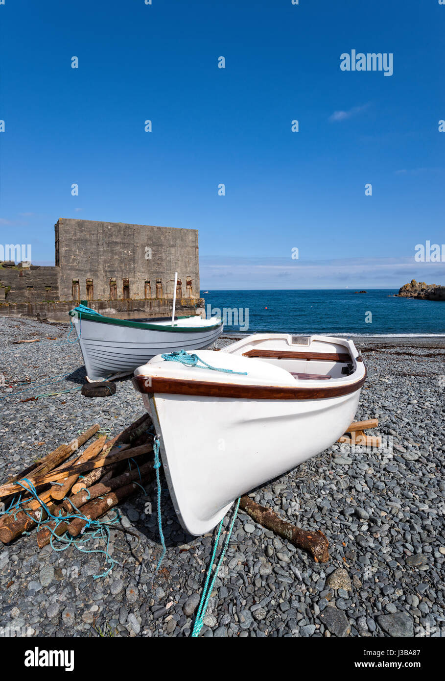 Barche Fisning sotto un cielo blu sulla spiaggia di Porthoustock sulla penisola di Lizard in Cornovaglia Foto Stock