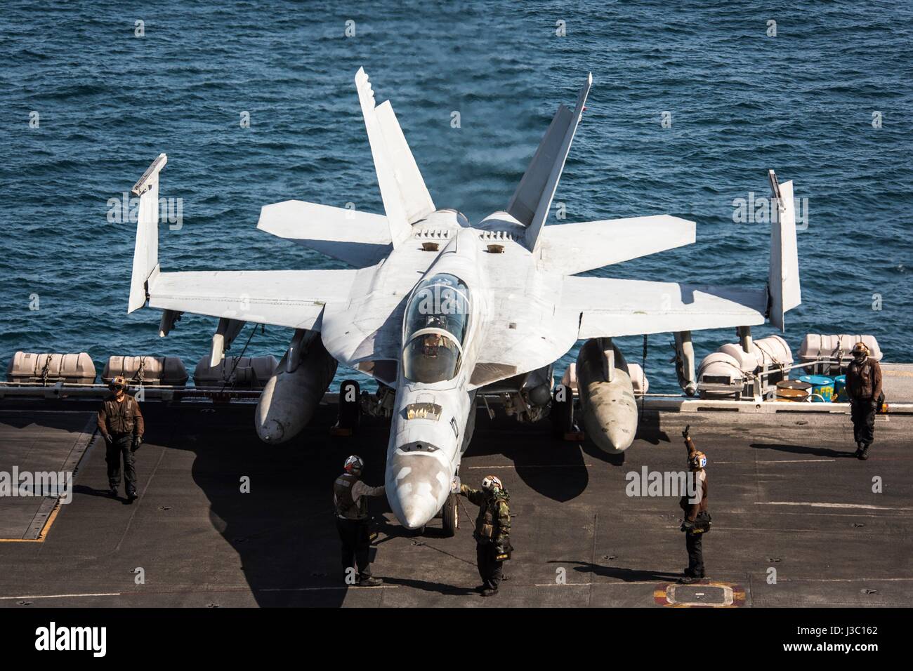 Stati Uniti I marinai della marina di eseguire controlli di volo su una F/A-18F Super Hornet fighter dal Bounty Hunters di Strike Fighter Squadron 2 prima di rullaggio per il decollo dal ponte di volo dell'Nimitz-class portaerei USS Carl Vinson in corso con un accompagnatore degli Stati Uniti e della Corea del Sud, navi da guerra durante patrol Maggio 2, 2017 al largo della costa della Corea. Foto Stock