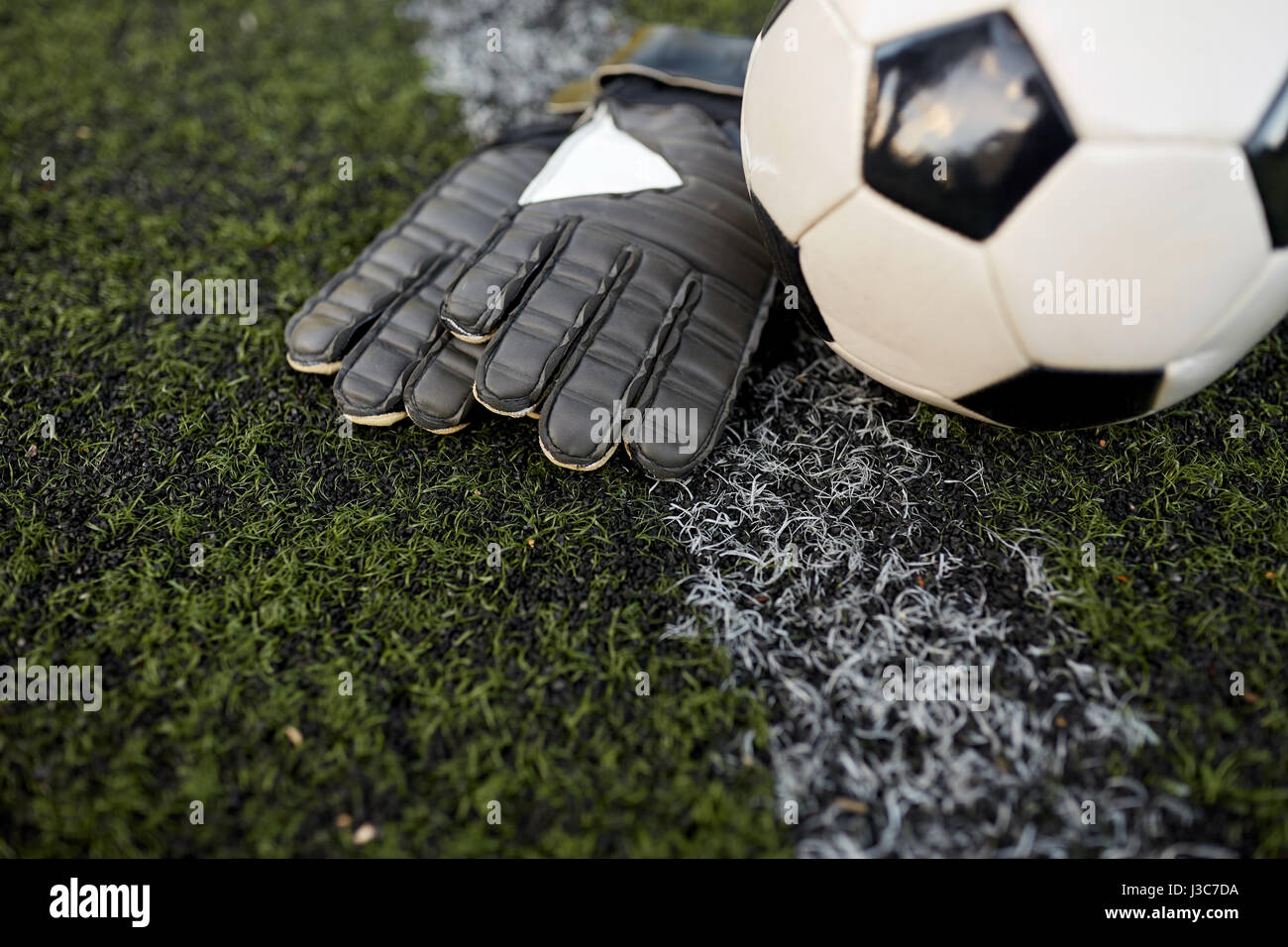 Pallone da calcio e il portiere guanti sul campo Foto Stock