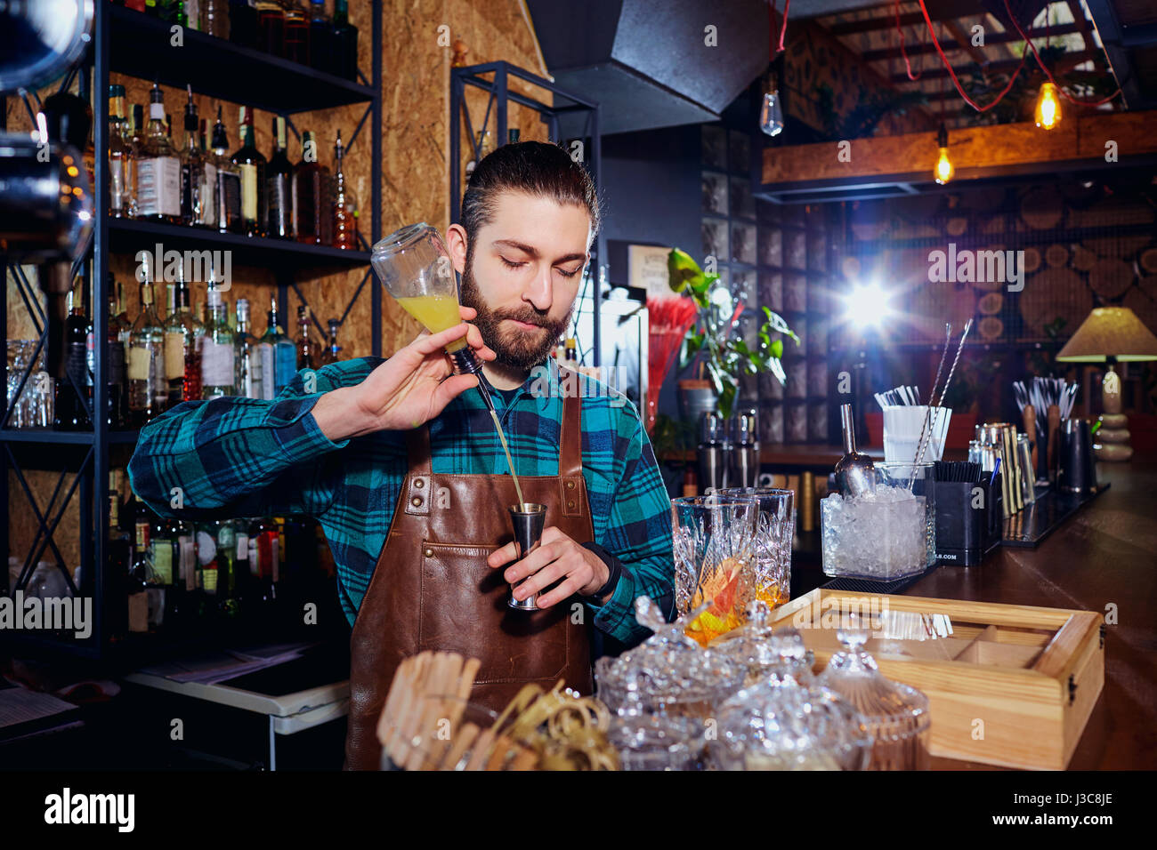 Barista hipster con la barba fa un cocktail alcoolico dietro il bancone del bar. Foto Stock