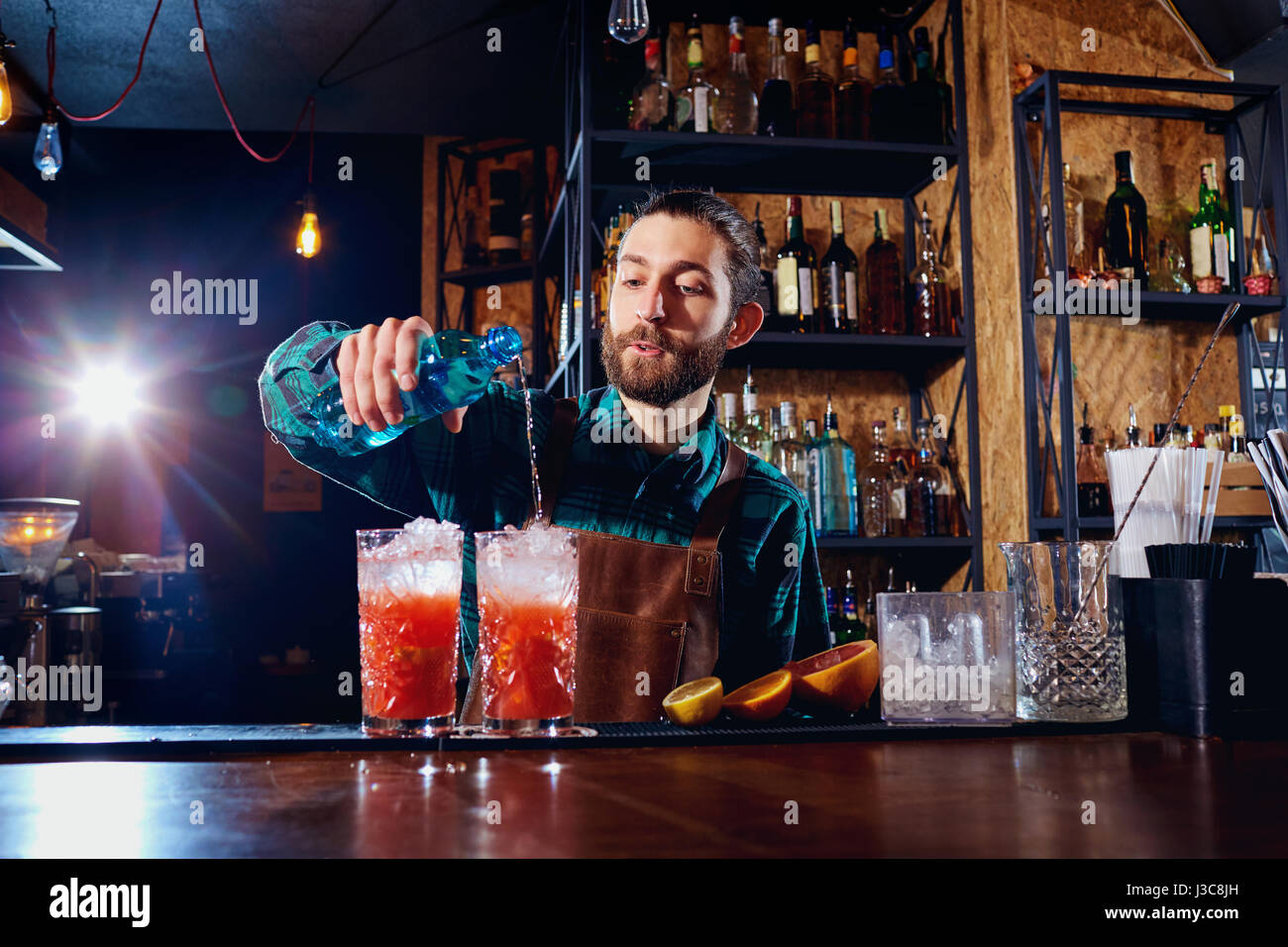 Barista hipster con la barba fa un cocktail alcoolico dietro il bancone del bar. Foto Stock