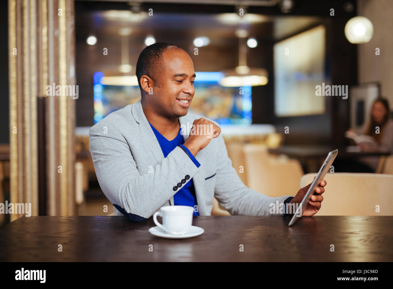 Immagine di felice giovane uomo utilizzando digitale compressa in cafe Foto Stock