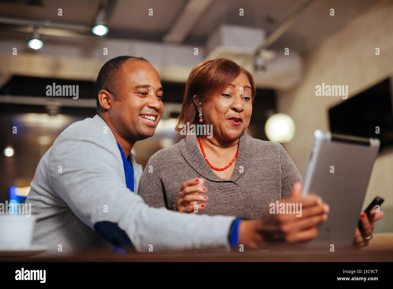 Una madre e figlio di tenere un computer tablet, parlando con gli amici Foto Stock