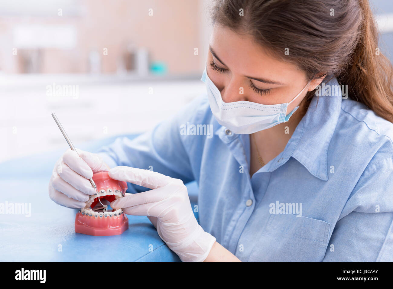 Ortodontista donna che lavorano su strumento modello di denti con metallo cablata bretelle dentali. Foto Stock