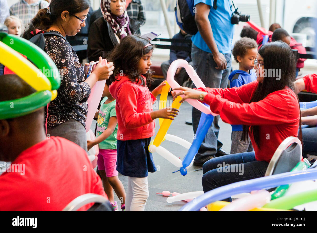 Piccola ragazza (5, 6 anni) ottenendo un carattere di palloncino realizzato in corrispondenza di un bambini evento - USA Foto Stock