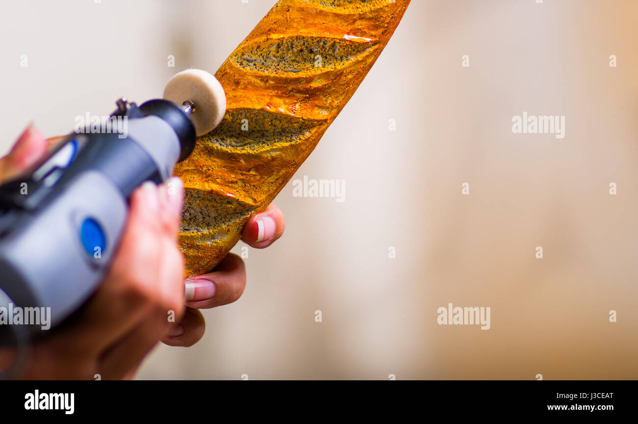 Un primo piano di una donna hardworker utilizzando una lucidatrice oltre un legno marrone pezzo Foto Stock