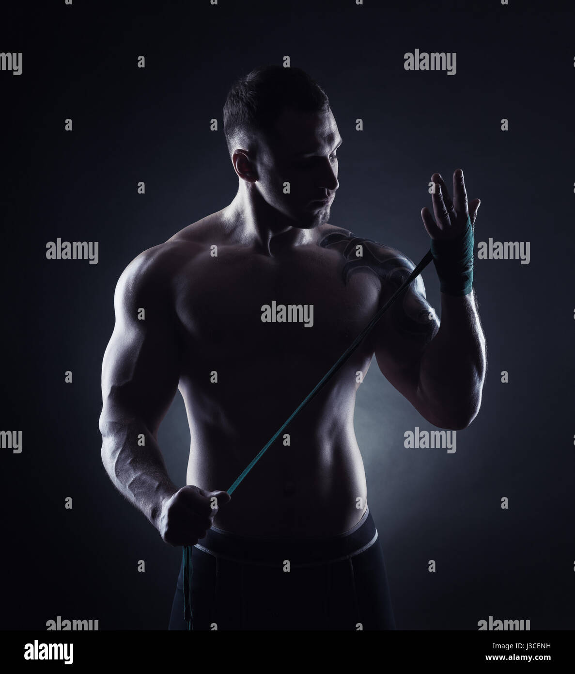 Boxer mettendo su cinghie preparando per combattere su sfondo scuro Foto Stock