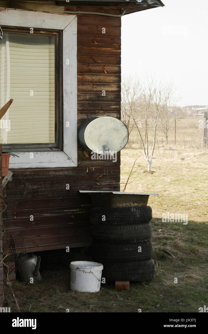 Rural montato a parete lavabo all'angolo di una casa in legno su strada Foto Stock
