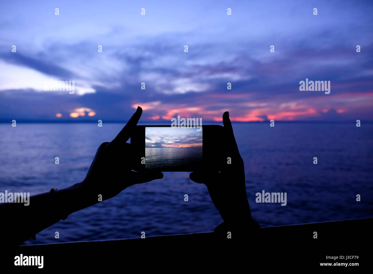Una donna lo scatto con uno smart phone tramonto sulla scena del lago Tanganica nel centro-occidentale della Tanzania Africa orientale Foto Stock