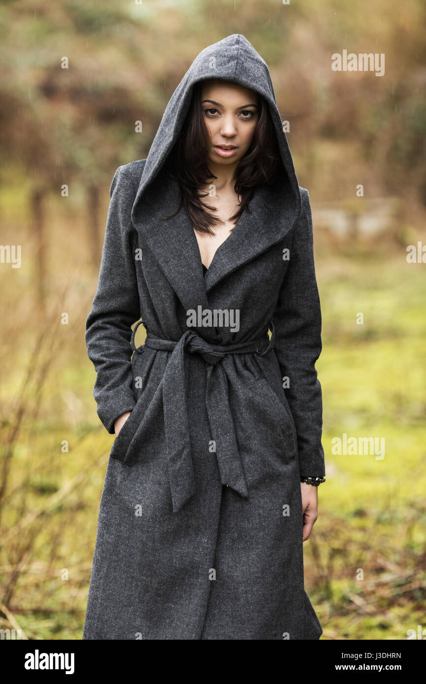 Una giovane donna che cammina nella campagna vestito con un cappotto con  cappuccio Foto stock - Alamy