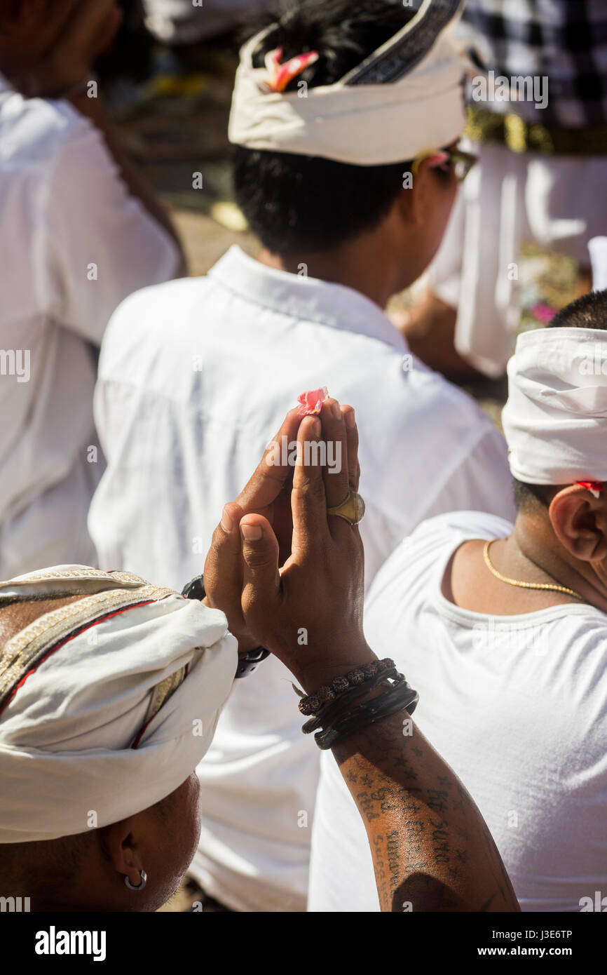 Uomini Balinese con le mani insieme nella preghiera durante una cerimonia religiosa vestito in stile Balinese abiti cerimoniali tenendo le mani sopra la testa Foto Stock