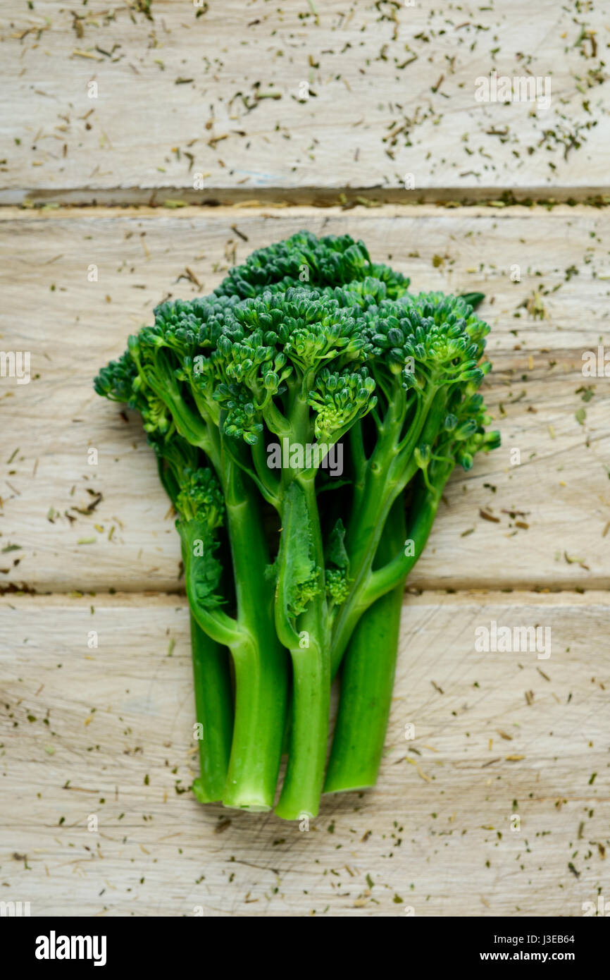 Alta angolazione di alcuni steli di broccolini su un bianco tavola in legno rustico Foto Stock