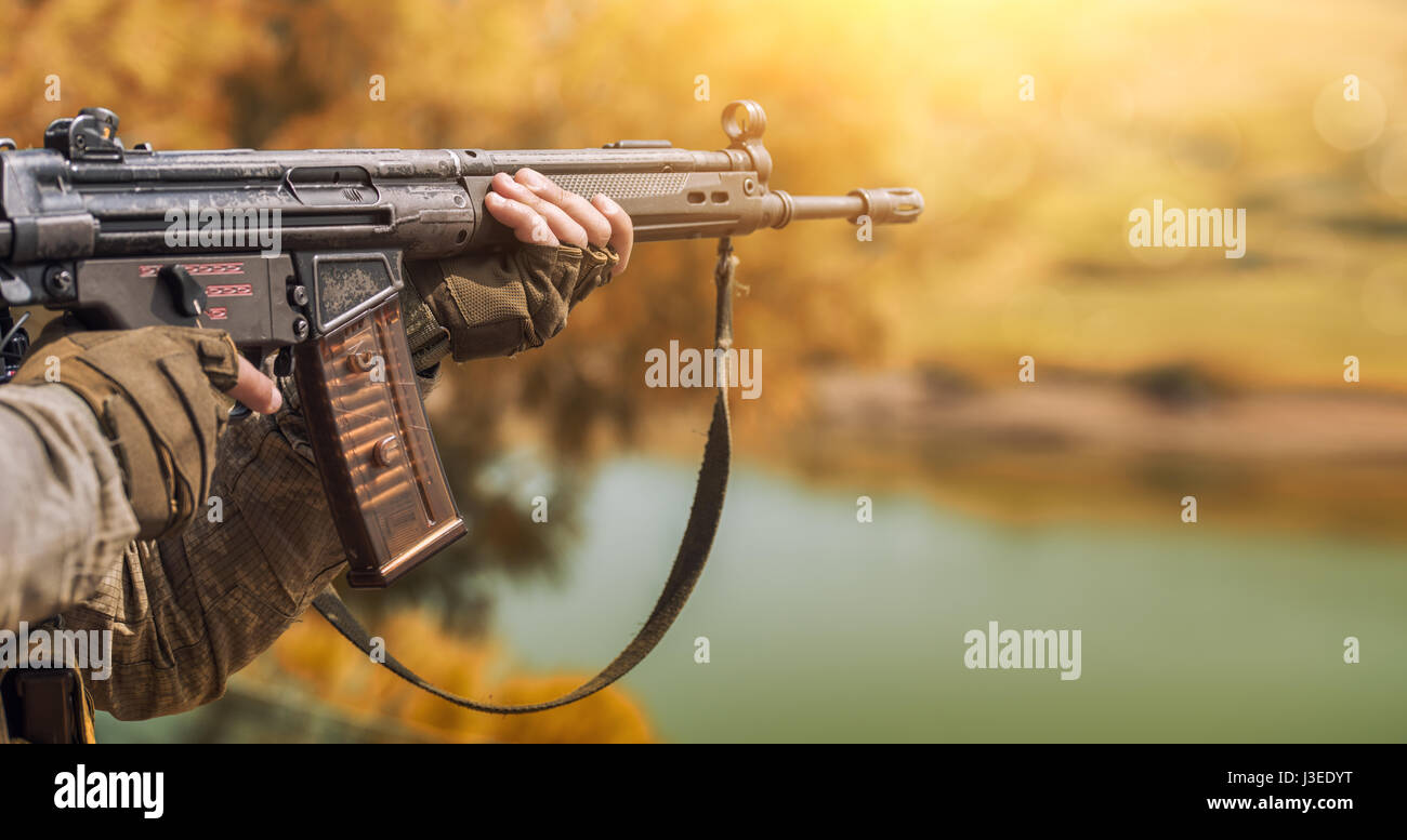 Il soldato in camuffamento e guanti di protezione, tenendo in mano una pistola. La zona di operazioni militari. Foto Stock