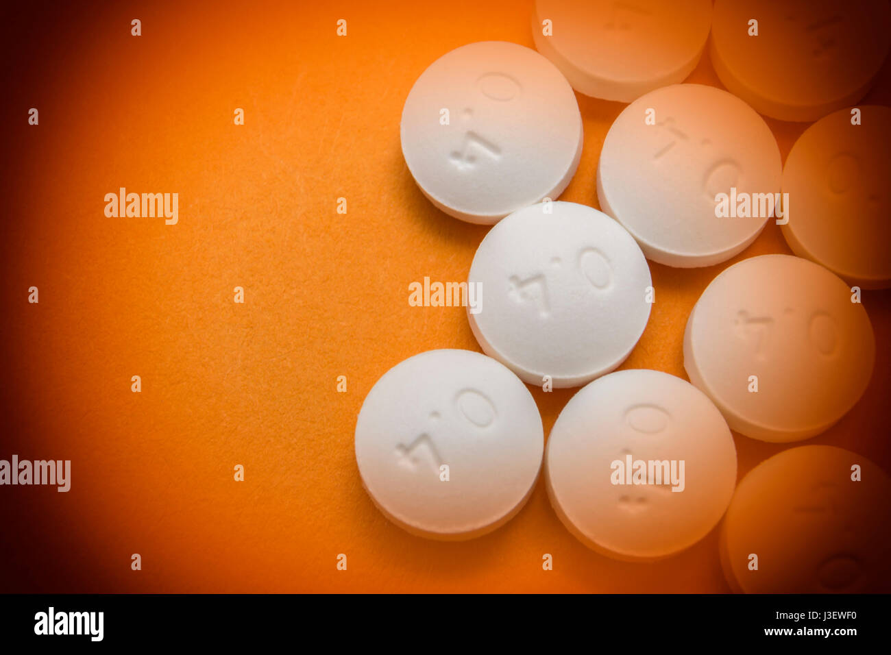 Alcune pillole bianchi allineati isolato su sfondo arancione Foto Stock