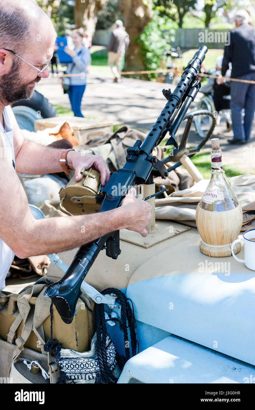 Saluto alla 40's rievocazione evento. Deserto area di ratti, uomo di regolazione e ingrassaggio macchina tedesca pistola sul cofano della jeep. Foto Stock