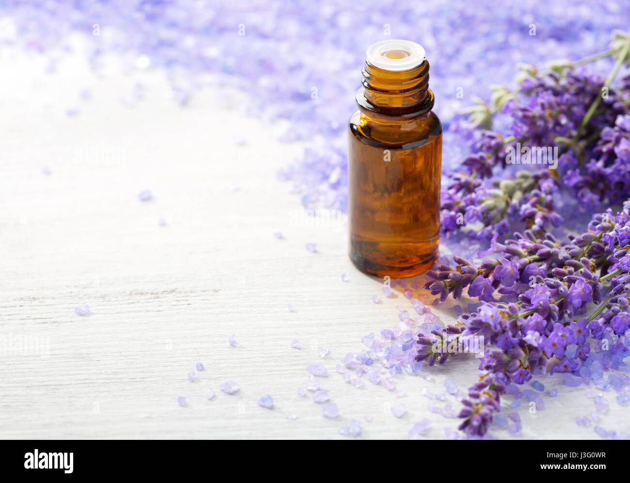 L'olio essenziale di lavanda, rametti di lavanda e minerali e sali da bagno sul tavolo di legno. Messa a fuoco selettiva Foto Stock