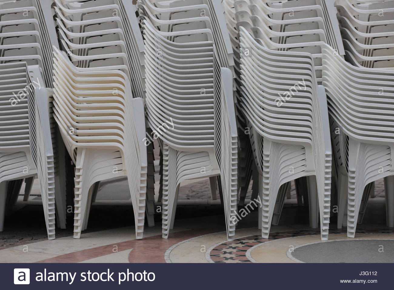 Sedie in plastica bianca impilati uno sull'altro prima di un evento Foto Stock