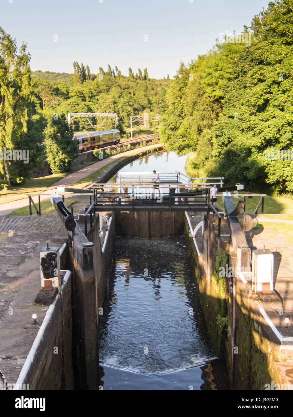 A nord del trasporto ferroviario di passeggeri di treno sulla Airedale linea ferroviaria passa il volo della scalinata si blocca a Kirkstall Forge sul Leeds e Liverpool Canal. Foto Stock
