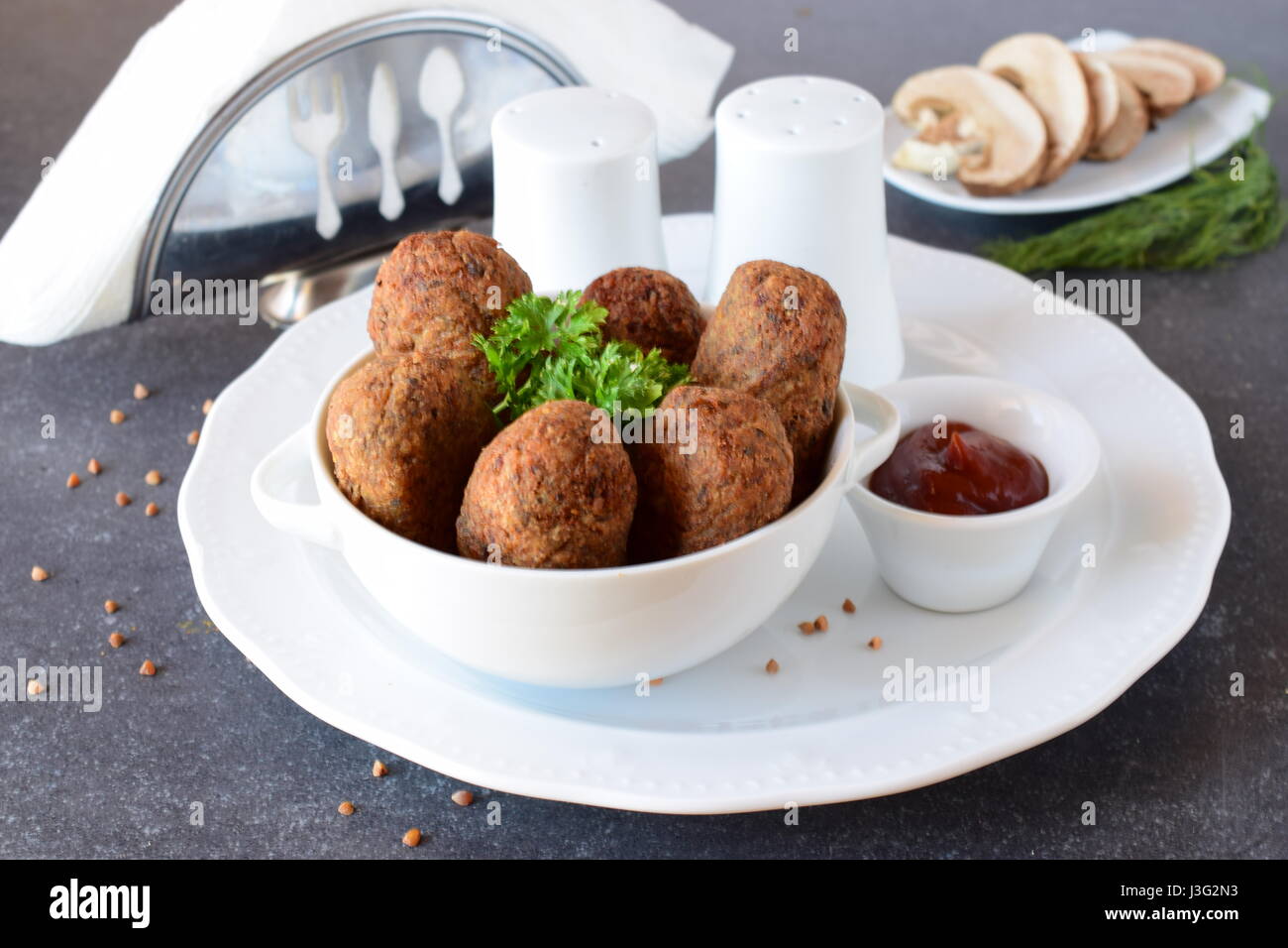 Sfere con il grano saraceno e i funghi in una ciotola bianco su un grigio Sfondo astratto. Dieta. Il digiuno del cibo. Il mangiare sano concetto Foto Stock