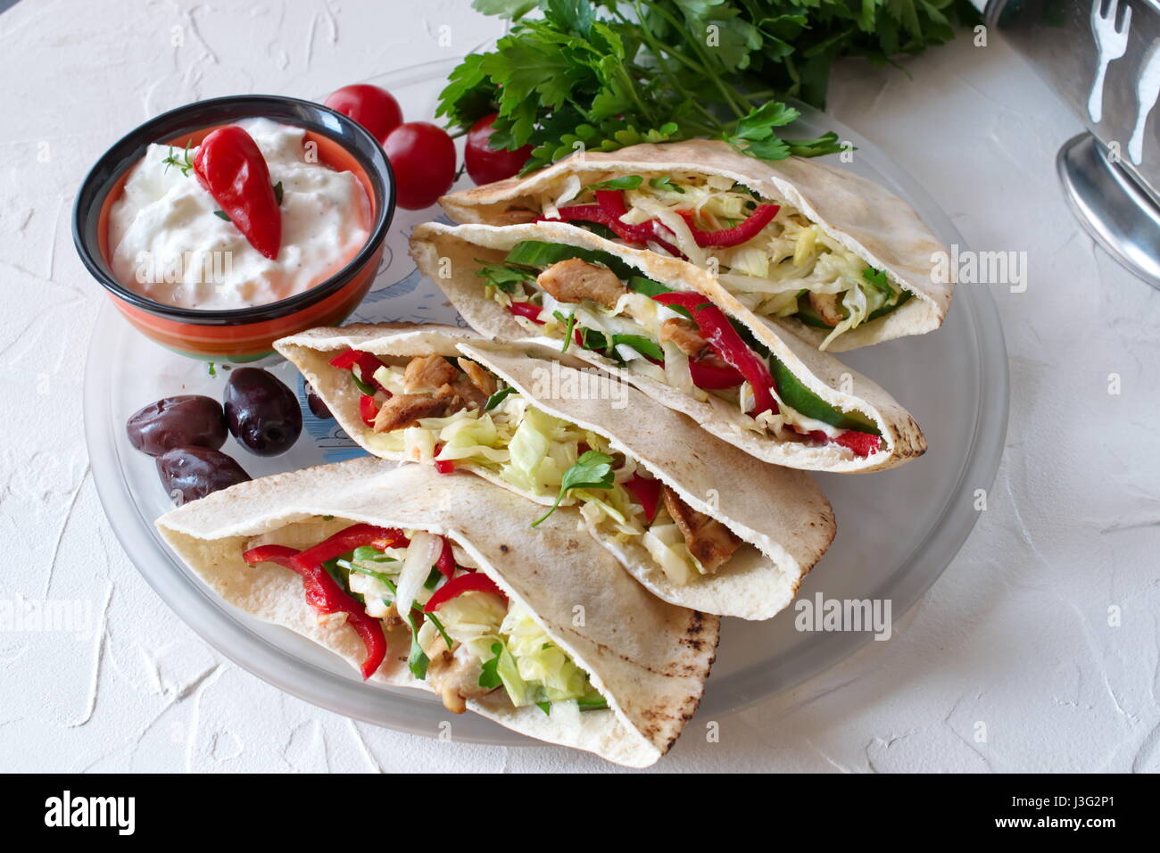 Pita riempito con petto di pollo alla brace, insalate fresche, cetriolo, paprica dolce, cipolla e salsa di yogurt su un astratto bianco sullo sfondo. Cucina casalinga. Foto Stock