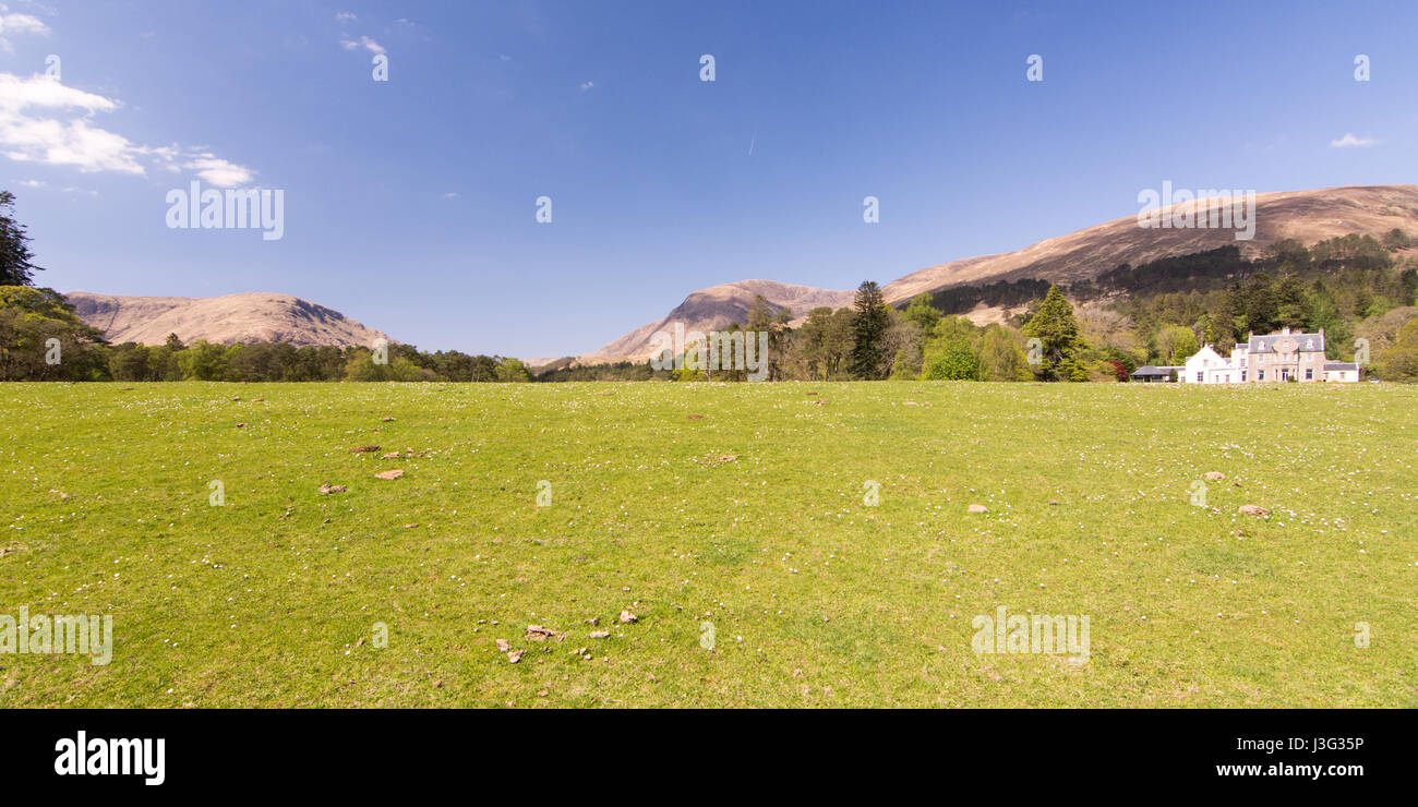 Una casa è accoccolato sotto le montagne a Cona Glen nel West Highlands della Scozia. Foto Stock