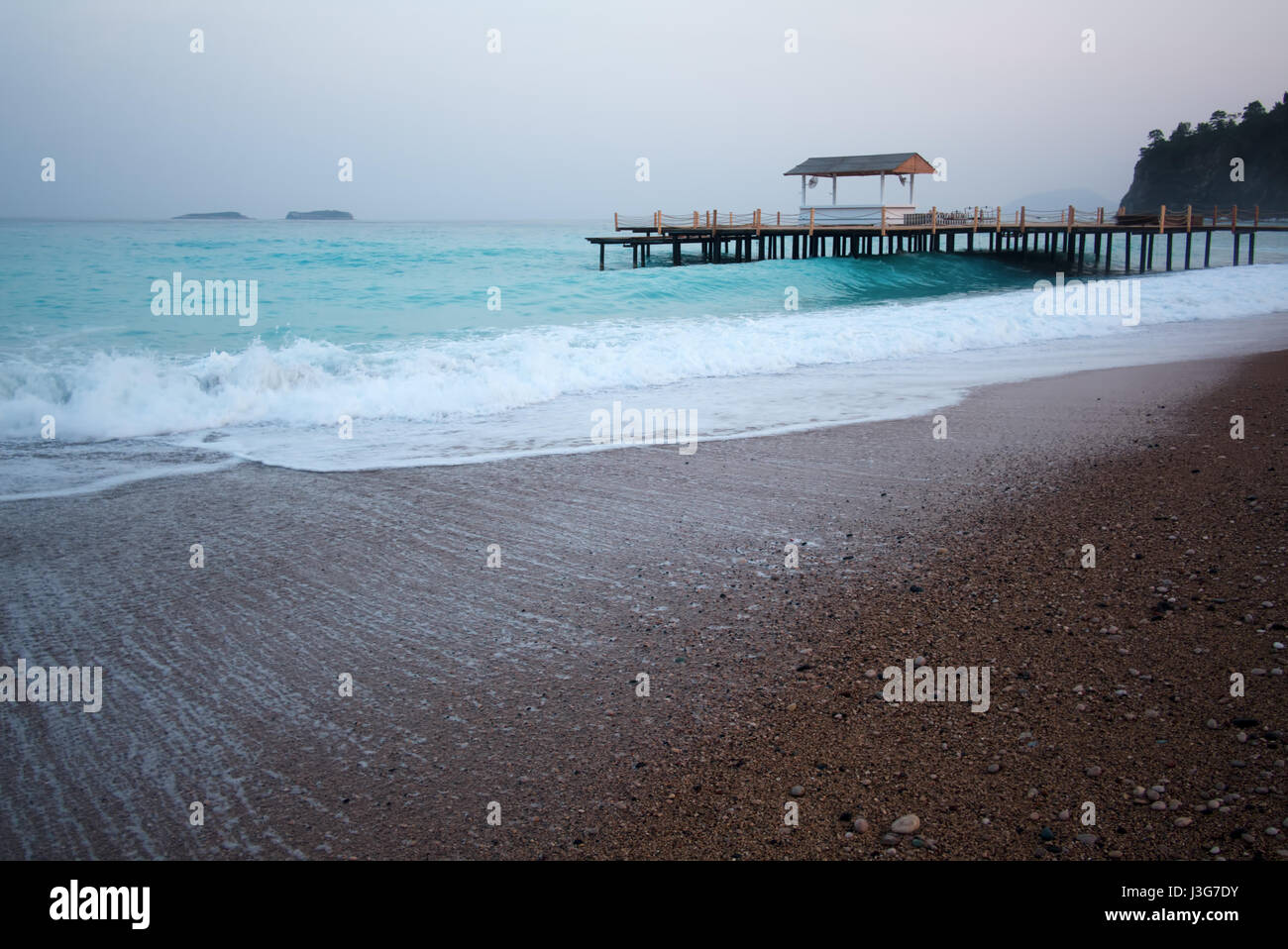 Estate arbor sulla spiaggia. Vista mozzafiato sul mar Mediterraneo. Bianco molo in legno sul tempo di sera Foto Stock
