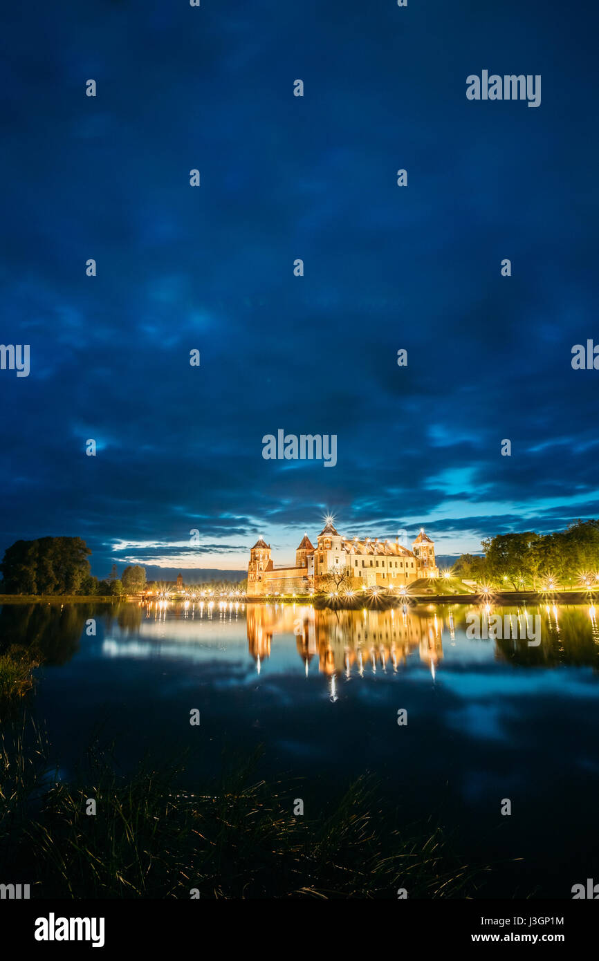 Mir, Bielorussia. Complesso del Castello di Mir In brillante illuminazione serale con candelette di riflessioni sul lago di acqua. Famoso punto di riferimento, antico monumento gotico di Feuda Foto Stock