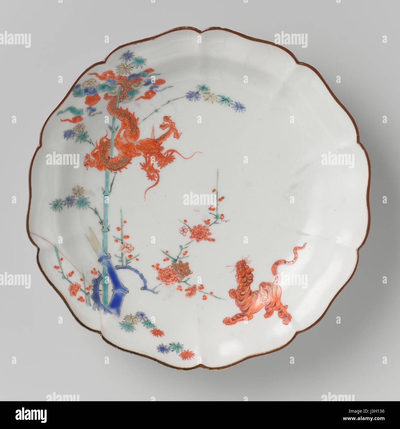 Questo pezzo, situato nel Rijksmuseum, presenta un design intricato con un drago, una tigre, un bambù e prunus. Riflette i tradizionali motivi artistici asiatici, comunemente usati negli oggetti decorativi durante la dinastia Qing o periodi simili, mostrando la miscela di natura e mitologia. Foto Stock