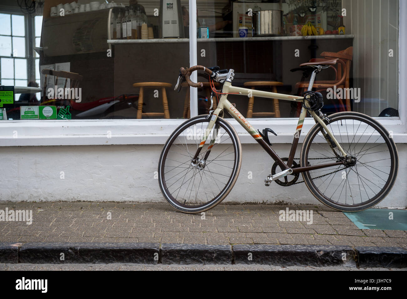 Un stile vintage bicicletta si appoggia contro una finestra cafe in Tenby, Pembrokeshire, Wales, Regno Unito Foto Stock