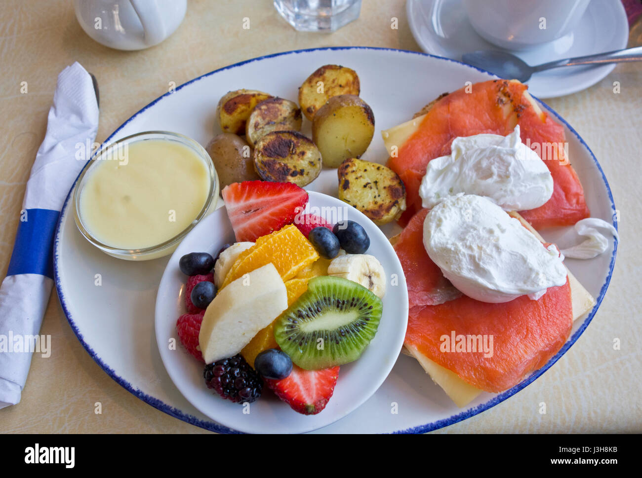 Delizioso salmone affumicato uova Benedict con frutta e patate. Foto Stock