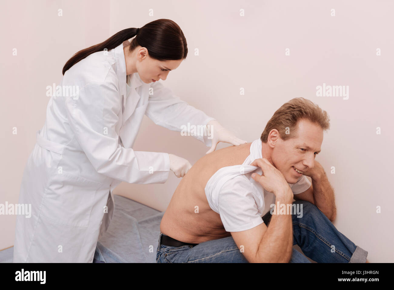 Sporgiti in avanti un po'. Turbato uomo di mezza età in posa per in modo speciale per lo specialista di esaminare e trattare la sua spina dorsale Foto Stock