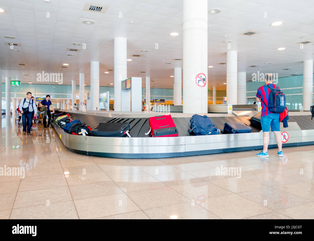 Barcellona, Spagna - 8 agosto, 2015: Nastro trasportatore per gli arrivi con bagagli valigie e persone intorno in attesa all'interno della grande e luminosa sala colorata ad aria Foto Stock