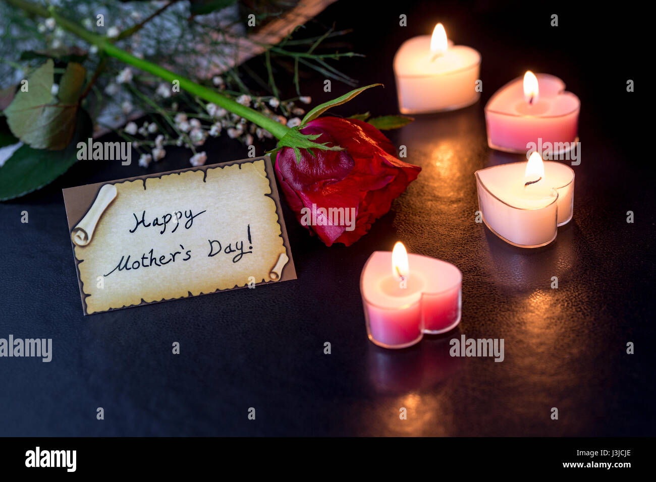 Felice Festa della mamma card con rosa a forma di cuore di candele nelle tenebre Foto Stock