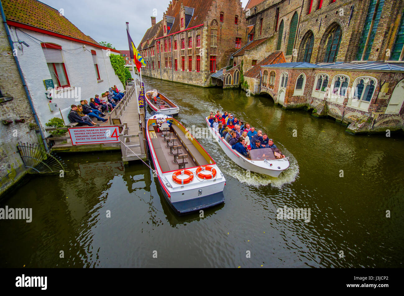 Bruges, Belgio - 11 August, 2015: imbarcazione turistica passando attraverso il canale circondato da una spettacolare architettura antica su entrambi i lati. Foto Stock